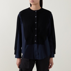 Model wearing HIGH black wool shirt with contrast navy cotton panel hem, collarless neckline and button front fastening