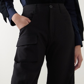 Model wearing HIGH black cargo trousers with side flap pockets, styled with a navy blue top. Straight-leg fit, high-rise waist.