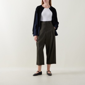 Model wearing HIGH khaki wide-leg cropped wool-blend trousers, styled with a white top, navy jacket and black mary jane flats.