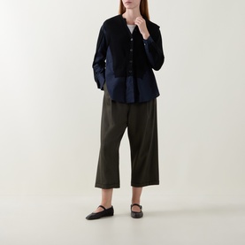 Model wearing HIGH khaki wide-leg cropped trousers in wool-lyocell blend, styled with a navy jacket and black flat shoes.