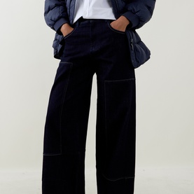 Model wearing HIGH navy wide-leg cotton trousers with contrast stitching, styled with a white tee and quilted jacket