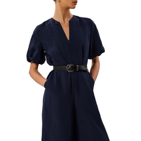 Model wearing Whistles blue short puff-sleeve V-neck dress with black leather belt, cropped wide-leg silhouette visible
