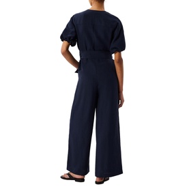 Model wearing Whistles blue wide-leg jumpsuit with puff sleeves and belted waist, styled with black flat sandals, back view