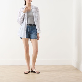 Model wearing Rag & Bone flora denim shorts with a striped shirt, grey top, and tan flat sandals.