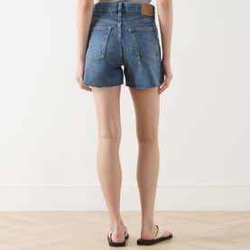 Model wearing Rag & Bone flora denim shorts, rear view, high-waisted with back pockets, styled with black flat sandals.