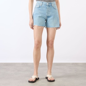 Model wearing Rag & Bone light blue denim shorts with raw frayed hem and high waist, styled with black strap flat sandals.