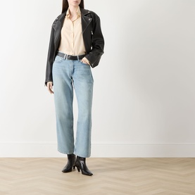 Model wearing Rag & Bone straight leg jeans in light denim, styled with a black leather jacket, peach shirt and black heeled boots.