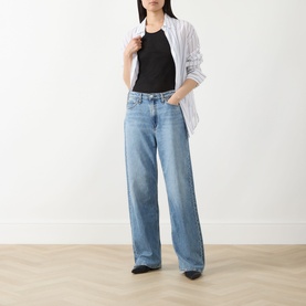 Model wearing Rag & Bone Wide Leg Jeans in lyon, paired with a black top and white striped shirt, with black pointed-toe flats.
