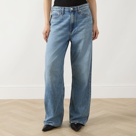 Model wearing Rag & Bone Wide Leg Jeans in lyon blue, relaxed fit with subtle fading, paired with black pointed-toe flats and black top.