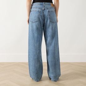 Model wearing Rag & Bone Wide Leg Jeans in lyon blue denim, rear view showing relaxed fit and wide-leg silhouette