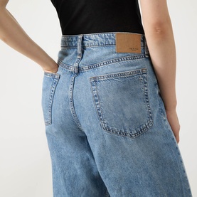 Model wearing Rag & Bone Wide Leg Jeans in lyon blue, rear view showing back pockets and leather logo patch waistband.