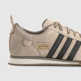 Adidas Samba trainer in Crystal Linen, dark brown suede upper with three stripes, gold branding detail and off-white sole, close-up shot.
