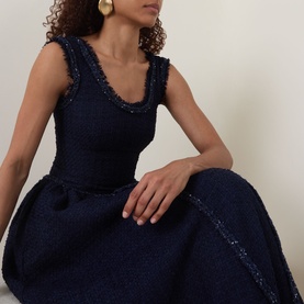 Model wearing Self-Portrait Boucl&eacute; Flared Dress in navy with scoop neckline, frayed trims, and glittering embellishment; gold earrings visible