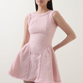Model wearing Self-Portrait pink boucl&eacute; mini dress with sleeveless design, fitted bodice, and flared skirt with seam detailing.