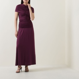 Model wearing Self-Portrait burgundy maxi dress with ruched short-sleeve bodice and flared skirt, styled with black strappy heels