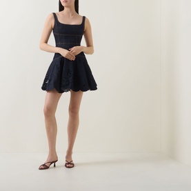 Model wearing Self-Portrait blue mini dress with square neckline and broderie anglaise flared skirt, styled with brown strappy heeled sandals