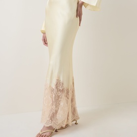 Model wearing Self-Portrait yellow viscose maxi dress with cream lace hem detail, styled with strappy heeled sandals.