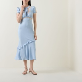 Model wearing Self-Portrait blue midi dress with lace trim, puff sleeves, and asymmetric ruffle hem, styled with strappy heeled sandals