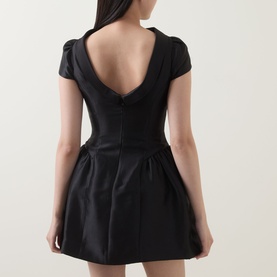 Model wearing Self-Portrait black mini dress with deep V-back, cap sleeves, fitted bodice and full skirt in polyester fabric.