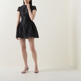Model wearing Self-Portrait black structured mini dress with cap sleeves and voluminous skirt, styled with strappy heeled sandals.