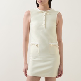 Model wearing Self-Portrait yellow sleeveless mini dress with button placket, satin-trim patch pockets, and round neckline.