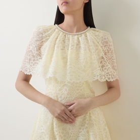 Model wearing Self-Portrait yellow lace dress with tiered cape overlay, scalloped hem detail and pearl neckline trim.