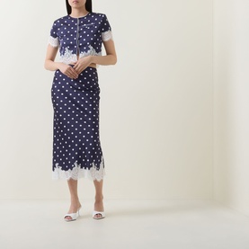 Model wearing Self-Portrait navy polka dot midi skirt with white lace hem trim, styled with matching top and white heeled mules