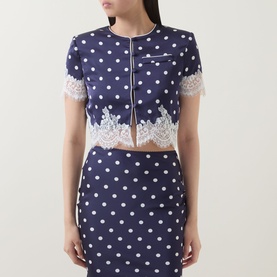 Model wearing Self-Portrait navy polka dot cropped top with white lace trim hem and cuffs, styled with matching polka dot mini skirt.
