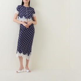 Model wearing Self-Portrait navy polka dot top with white lace trim, styled with matching midi skirt and white heeled mules