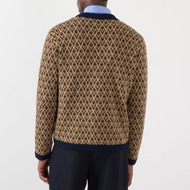 Model wearing Valentino camel wool cardigan with navy VLogo diamond jacquard pattern, styled with blue collar shirt and navy trousers