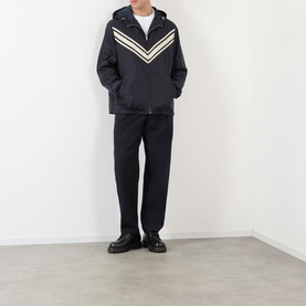 Model wearing Valentino dark marine casual jacket with beige chevron stripe detail and hood, styled with black trousers and leather shoes