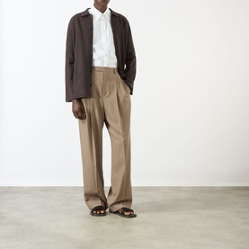 Model wearing Valentino Patch Pocket Knitted Polo Cardigan in brown, styled with white shirt, taupe wide-leg trousers and brown sandals.
