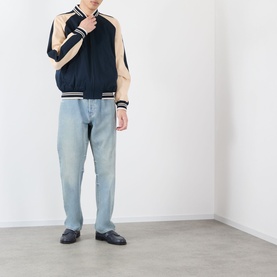 Model wearing Valentino navy casual jacket with beige contrast panels and stripe trim, styled with light blue jeans and black loafers