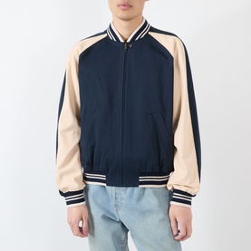 Model wearing Valentino navy casual jacket with contrast beige raglan sleeves and striped ribbed collar, cuffs and hem, styled with light blue jeans