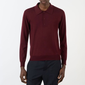 Model wearing Valentino Logo Knitted Polo Sweater in red with three-button placket and long sleeves, styled with navy trousers.