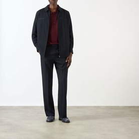Model wearing Valentino Logo Knitted Polo Sweater in red with dark jacket, tailored trousers, and black loafers.