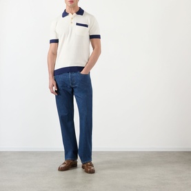 Model wearing Valentino cream cotton polo with navy contrast collar and trim, styled with blue jeans and brown loafers