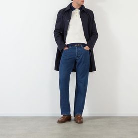 Model wearing Valentino cream cotton polo, styled with navy overcoat, blue jeans, and brown leather shoes.