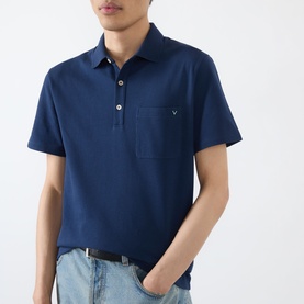 Model wearing Valentino indigo cotton polo shirt with chest pocket and VLogo detail, styled with light-wash jeans and black belt