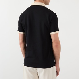 Model wearing Valentino V-Logo Polo Shirt in black with contrasting cream collar and cuffs, short sleeves, rear view, styled with cream trousers.