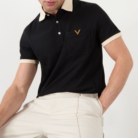 Model wearing Valentino V-Logo Polo Shirt in black with cream contrast collar, cuffs, and gold V-logo chest pocket, styled with ecru trousers