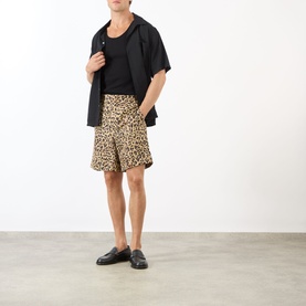 Model wearing Valentino Multicolor Animalier silk shorts with black open-collar shirt, black tank top, and black loafers.