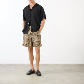 Model wearing Valentino Multicolor Animalier silk shorts, styled with a black short-sleeve shirt and black loafers.