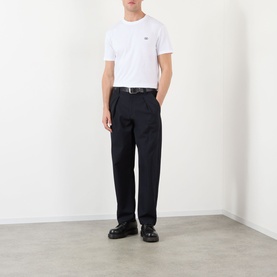 Model wearing Valentino white cotton T-shirt, styled with navy pleated trousers and black leather loafers.