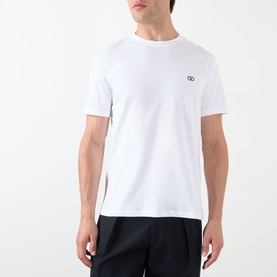 Model wearing Valentino white cotton crew neck T-shirt with tonal VV logo embroidery at chest, styled with navy trousers