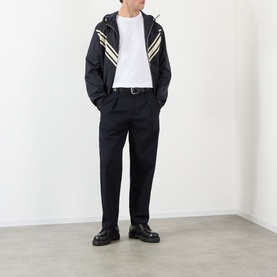 Model wearing Valentino white cotton T-shirt, styled with black zip-up hooded jacket with cream stripe detail and black tailored trousers.