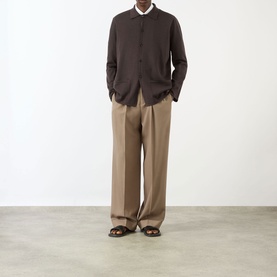 Model wearing Valentino Pleated Straight-Leg Trousers in camel wool, styled with dark brown shirt and sandals.