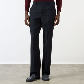 Model wearing Valentino Pressed Slim-Leg Trousers in storm blue wool with pressed creases, styled with dark loafers and burgundy top.