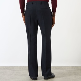 Model wearing Valentino Pressed Slim-Leg Trousers in storm blue wool, shown from rear, with pressed creases and clean hems, styled with dark shoes.
