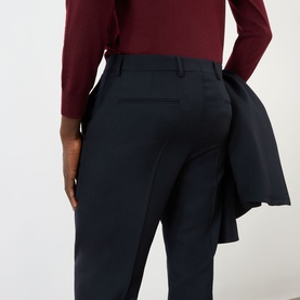 Model wearing Valentino Pressed Slim-Leg Trousers in storm blue wool, slim fit with pressed creases, styled with burgundy top and navy blazer.